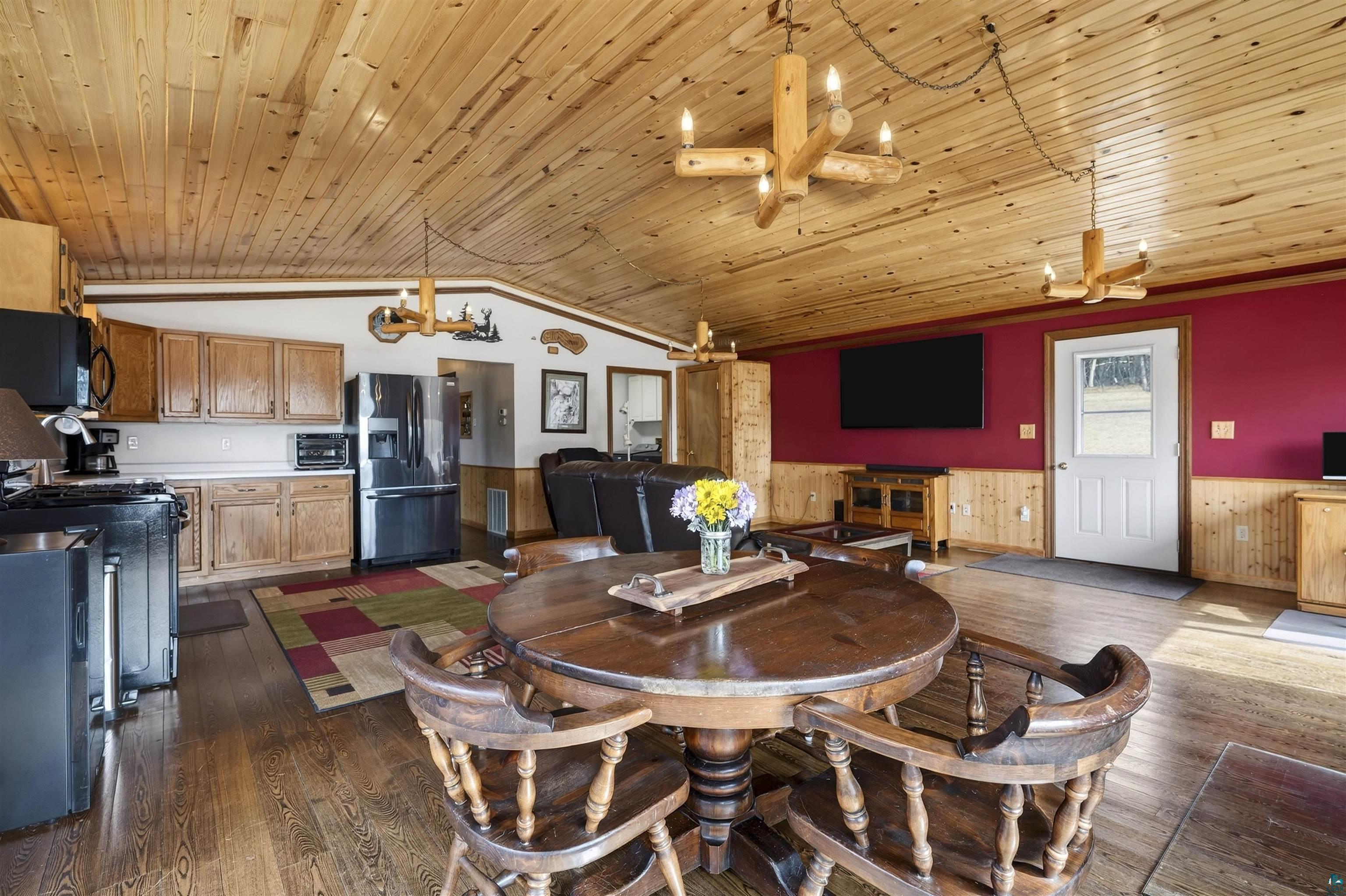 11702 East Mail Road Gordon, WI 54838 - Photo 35 of 49 Dining space featuring wainscoting, dark wood-style floors, hanging lights, wood walls, and wooden ceiling