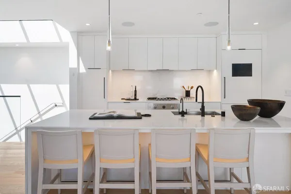a kitchen with stainless steel appliances kitchen island granite countertop a sink a stove a refrigerator and white cabinets with wooden floor
