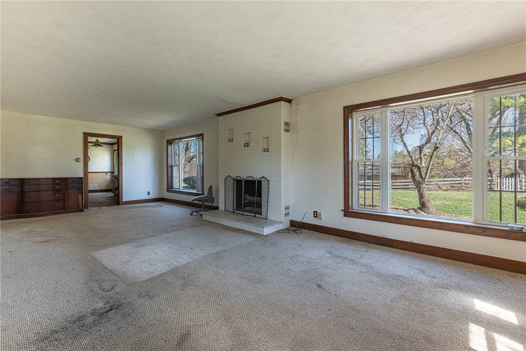 6885 Garber Road Clayton, OH 45415 - Photo 3 of 24 This spacious living area offers a cozy fireplace and expansive windows framing serene outdoor views.