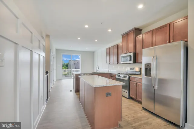 a kitchen with stainless steel appliances granite countertop a refrigerator a stove and a sink