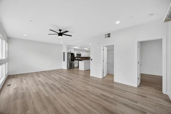 an empty room with wooden floor and a kitchen