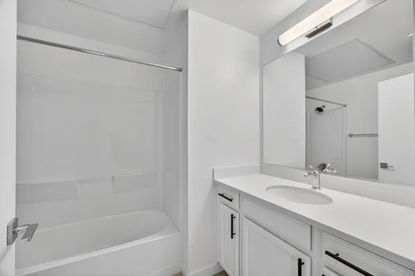 a bathroom with a granite countertop sink a mirror and a bathtub