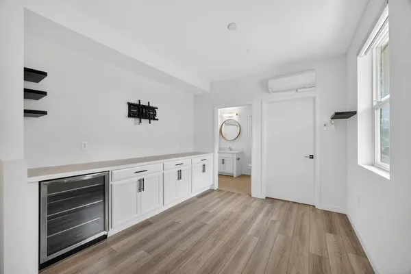 a hall with kitchen island white cabinets and stainless steel appliances