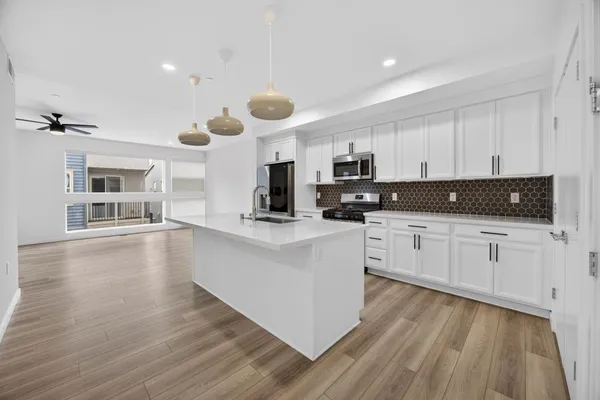 a kitchen with stainless steel appliances white cabinets and wooden floors