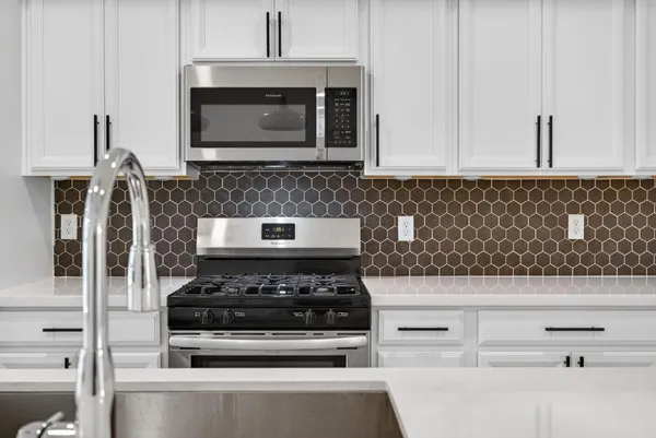 a kitchen with granite countertop white cabinets and black appliances