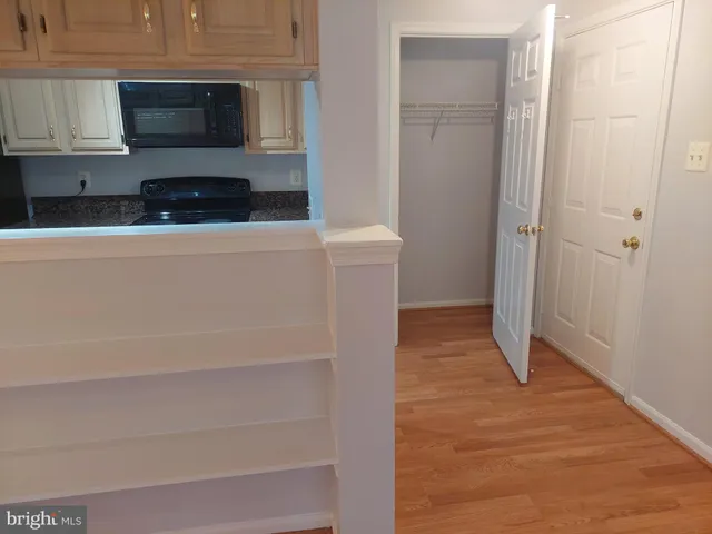 a view of an empty room with wooden floor and a cabinet