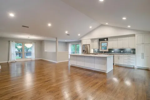 a view of kitchen with kitchen island granite countertop wooden floors and wide window