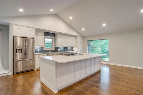 a kitchen with kitchen island white cabinets and stainless steel appliances