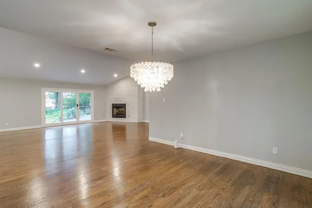 a view of a room with wooden floor fireplace and windows