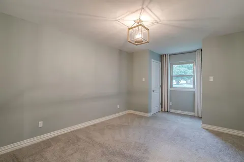 an empty room with a chandelier fan and a window