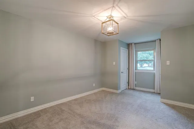 an empty room with a chandelier fan and a window