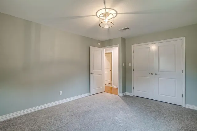 an empty room with a chandelier fan and closet area
