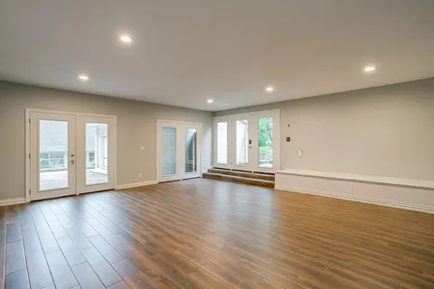 a view of an empty room with wooden floor and windows