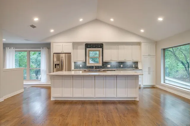 a large kitchen with granite countertop a large window and wooden floors