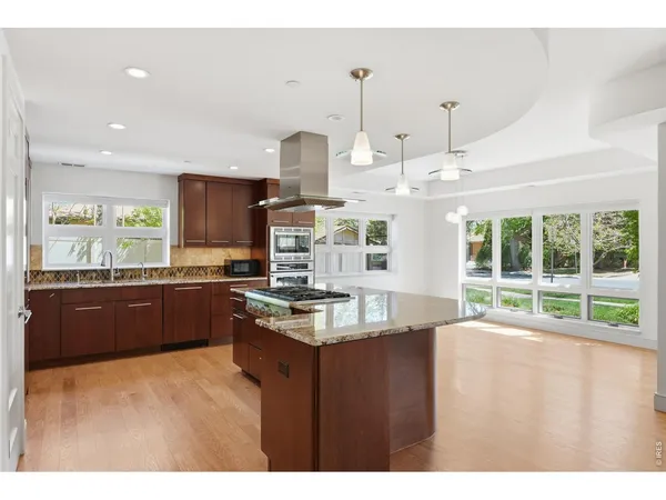 a open kitchen with stainless steel appliances granite countertop a refrigerator a sink dishwasher and a oven with wooden floor
