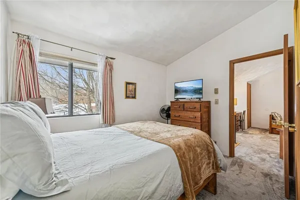 a bedroom with a bed and a large mirror next to a window