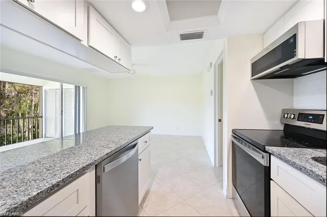 a kitchen with granite countertop stainless steel appliances a sink stove and cabinets