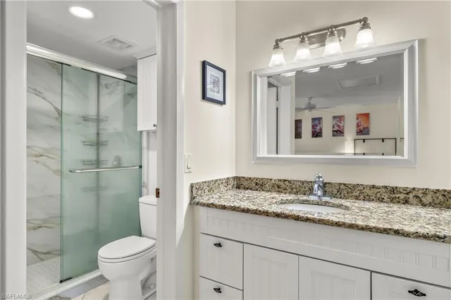 a bathroom with a granite countertop sink toilet and shower