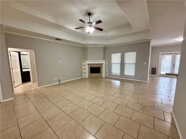 a view of an empty room with a fireplace and a ceiling fan