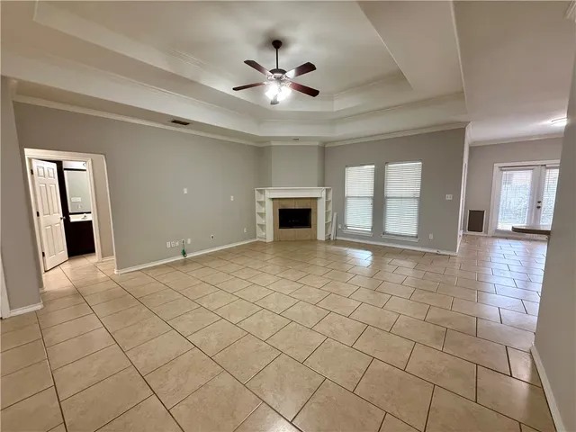 a view of an empty room with a fireplace and a ceiling fan