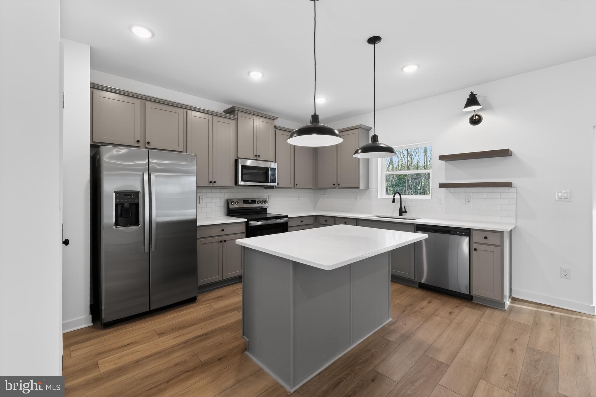 14956 Channel Run Ellendale, DE 19941 - Photo 7 of 28 a kitchen with stainless steel appliances granite countertop a sink a stove a refrigerator and island with wooden floor
