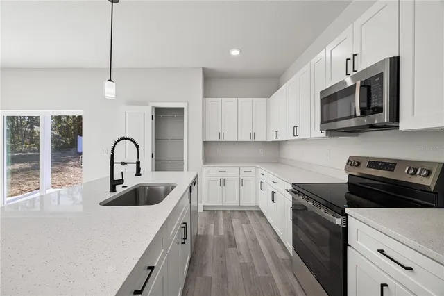 a kitchen with stainless steel appliances granite countertop a sink a stove top oven a counter space and cabinets