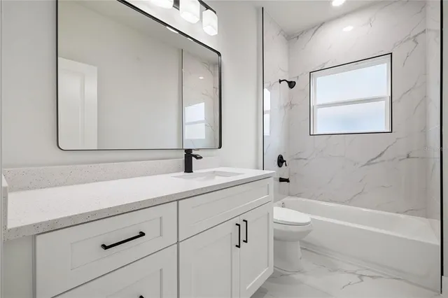 a bathroom with a double vanity sink a toilet and a bathtub