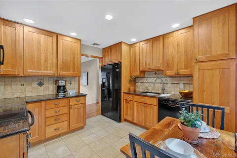 a kitchen with stainless steel appliances granite countertop a refrigerator a sink dishwasher and wooden cabinets with wooden floor