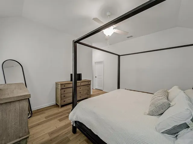 a bedroom with a bed and a dresser with wooden floor