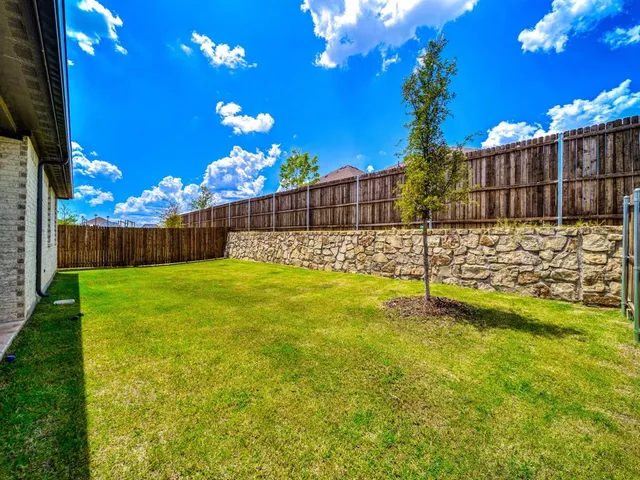 a view of a patio with a dining table and chairs under an umbrella with palm trees