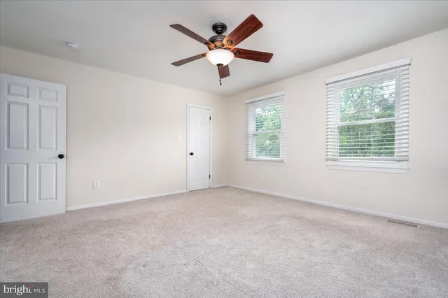 an empty room with ceiling fan and window