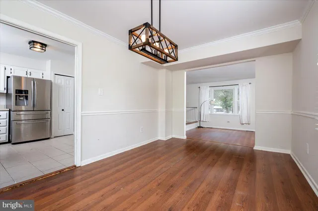 a view of a kitchen with a refrigerator a stove top oven and hallway