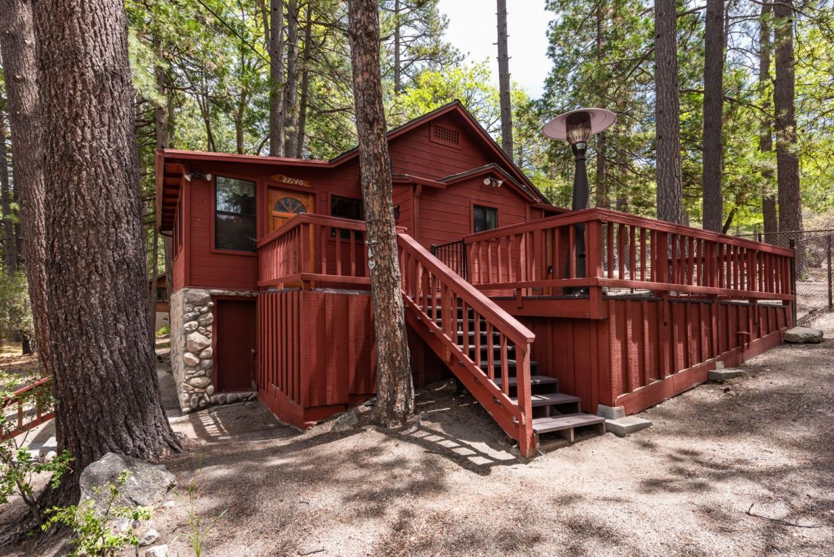 27140 Saunders Meadow Road Idyllwild, CA 92549 - Photo 1 of 25 a view of a wooden house with large trees and wooden fence