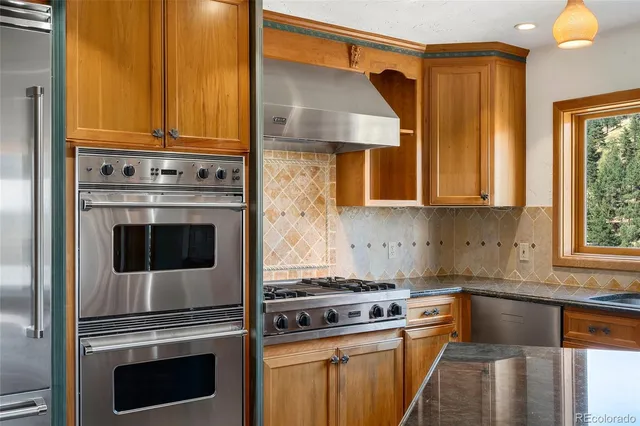 a kitchen with stainless steel appliances granite countertop a sink a refrigerator and a stove