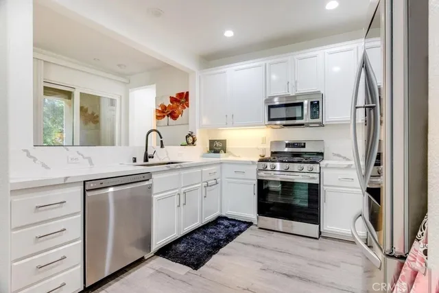 a kitchen with stainless steel appliances granite countertop a sink and a refrigerator