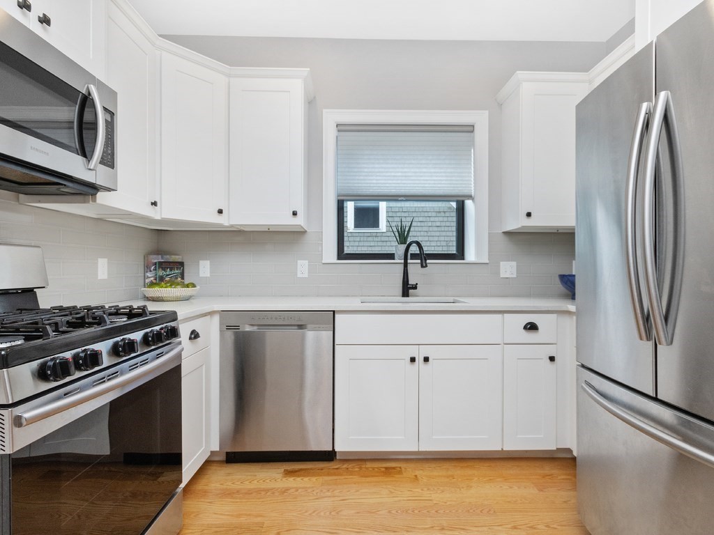 286 Summer Street, Unit 2 Somerville, MA 02144 - Photo 10 of 37 a kitchen with stainless steel appliances granite countertop a refrigerator a stove a sink and white cabinets