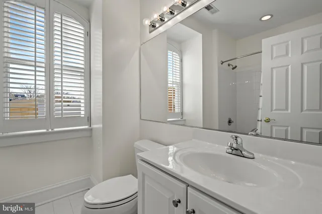 a bathroom with a toilet a sink a mirror and a window