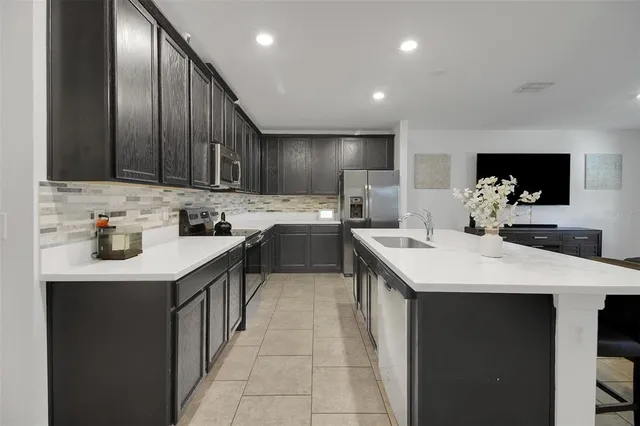 a kitchen with stainless steel appliances kitchen island granite countertop a refrigerator and a stove top oven