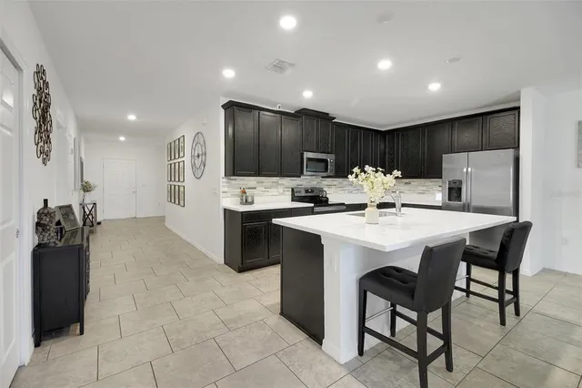a kitchen with a dining table chairs and refrigerator