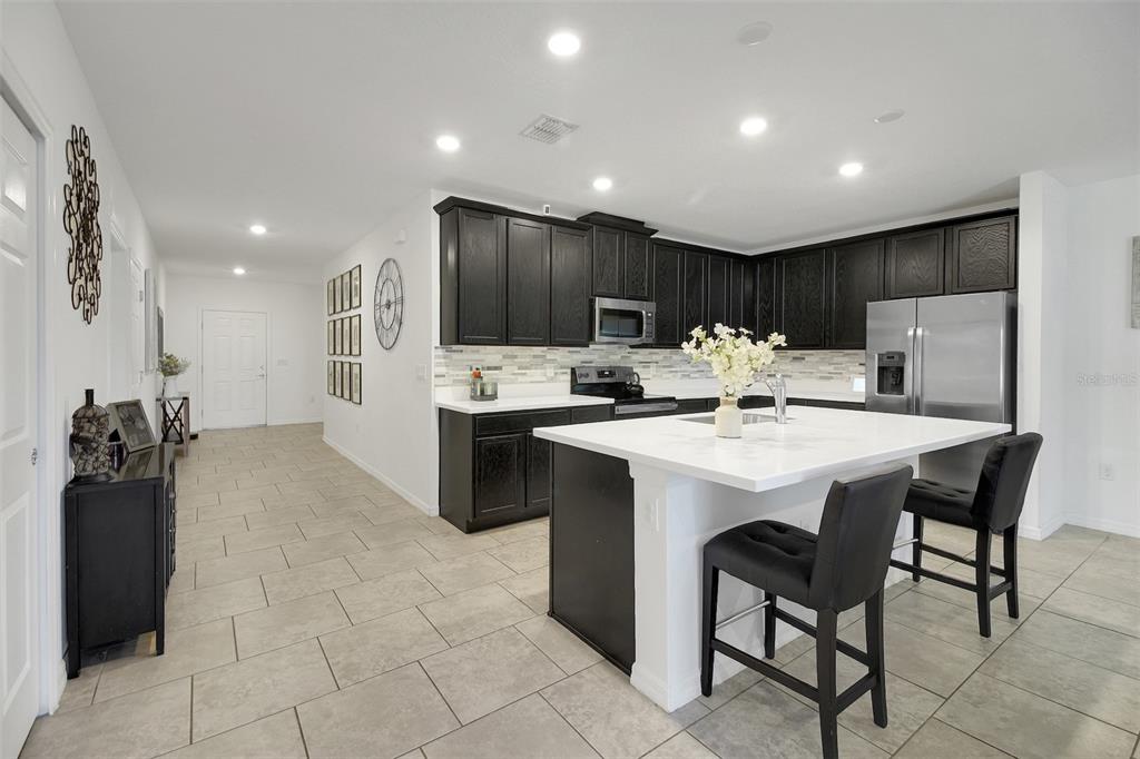 10121 Grande Loop Clermont, FL 34711 - Photo 12 of 30 a kitchen with stainless steel appliances kitchen island granite countertop a refrigerator and a stove top oven