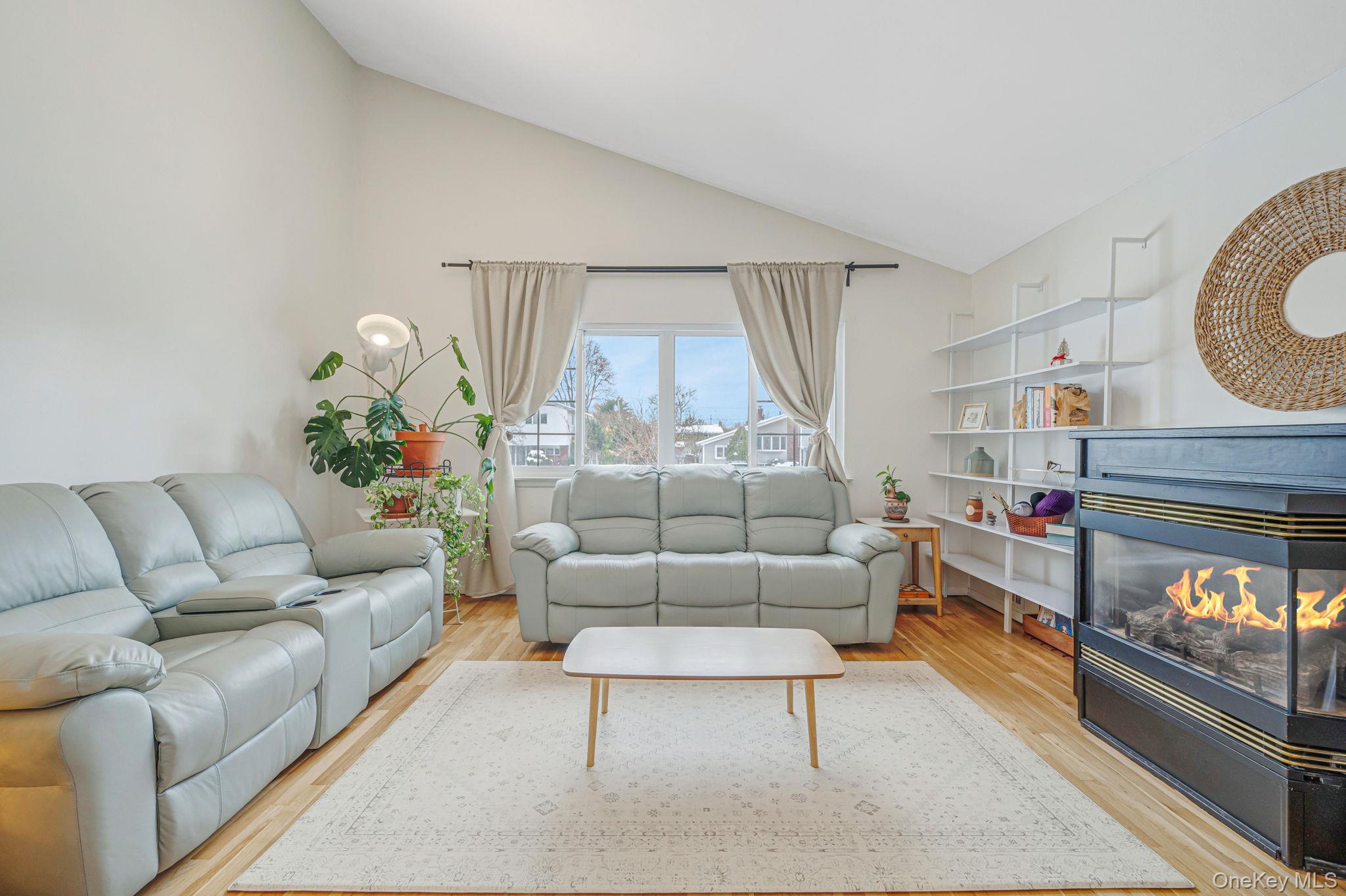 7 Seneca Drive Commack, NY 11725 - Photo 11 of 40 Main living area featuring a multi sided fireplace, light wood-style floors, and high vaulted ceiling