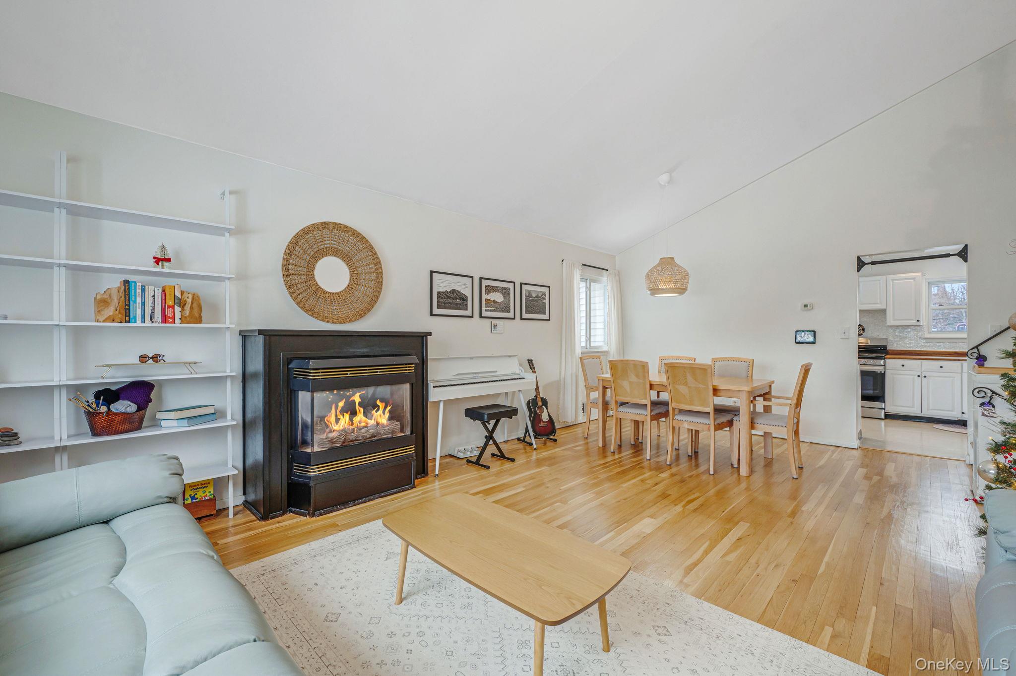 7 Seneca Drive Commack, NY 11725 - Photo 13 of 40 Main living area with light wood-style flooring, a multi sided fireplace, healthy amount of natural light, and high vaulted ceiling
