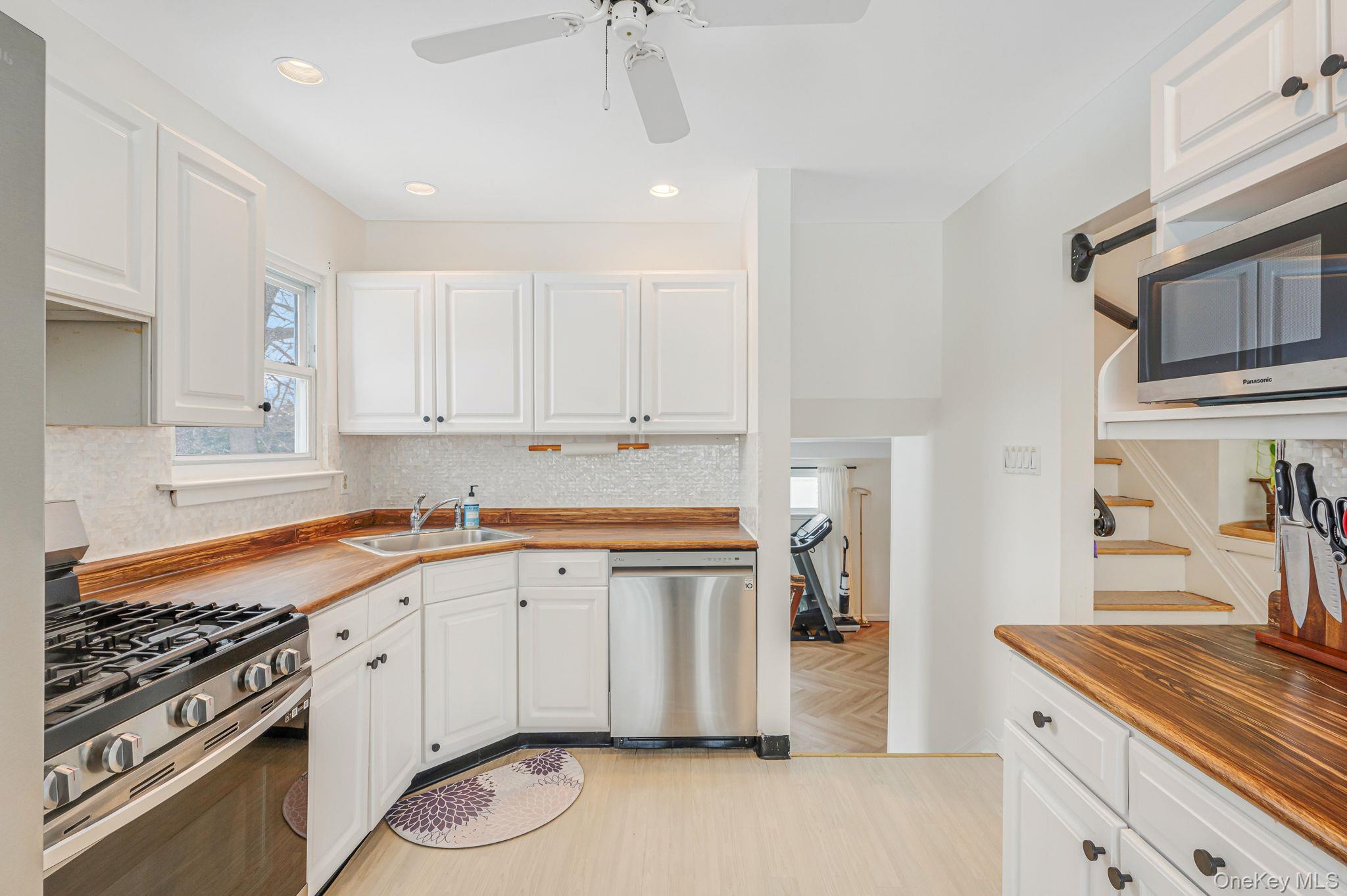 7 Seneca Drive Commack, NY 11725 - Photo 18 of 40 Kitchen with butcher block countertops, stainless steel appliances, white cabinetry, light wood-type flooring, and a ceiling fan
