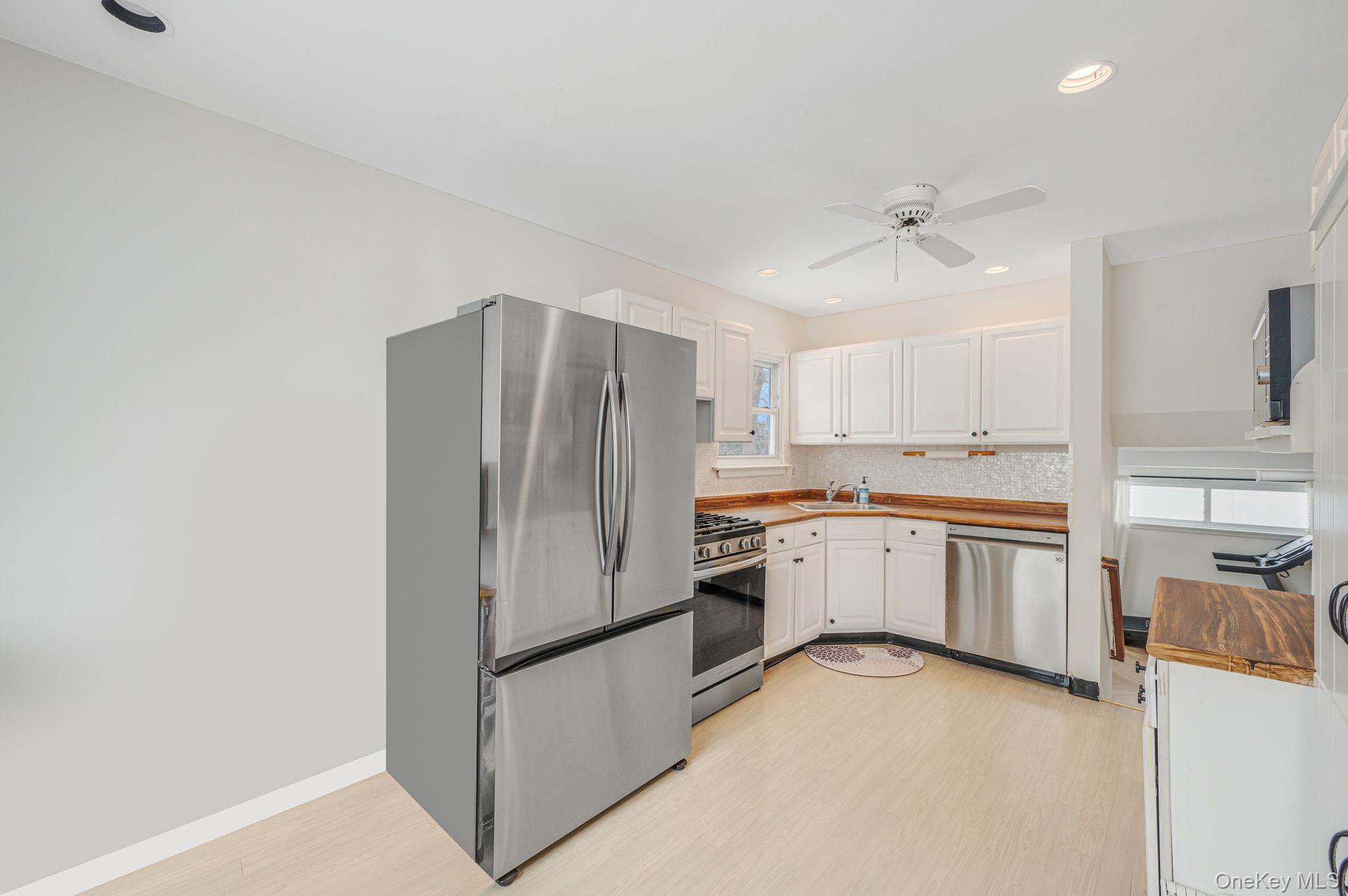 7 Seneca Drive Commack, NY 11725 - Photo 20 of 40 Kitchen with stainless steel appliances, white cabinetry, light wood-type flooring, recessed lighting, and a ceiling fan