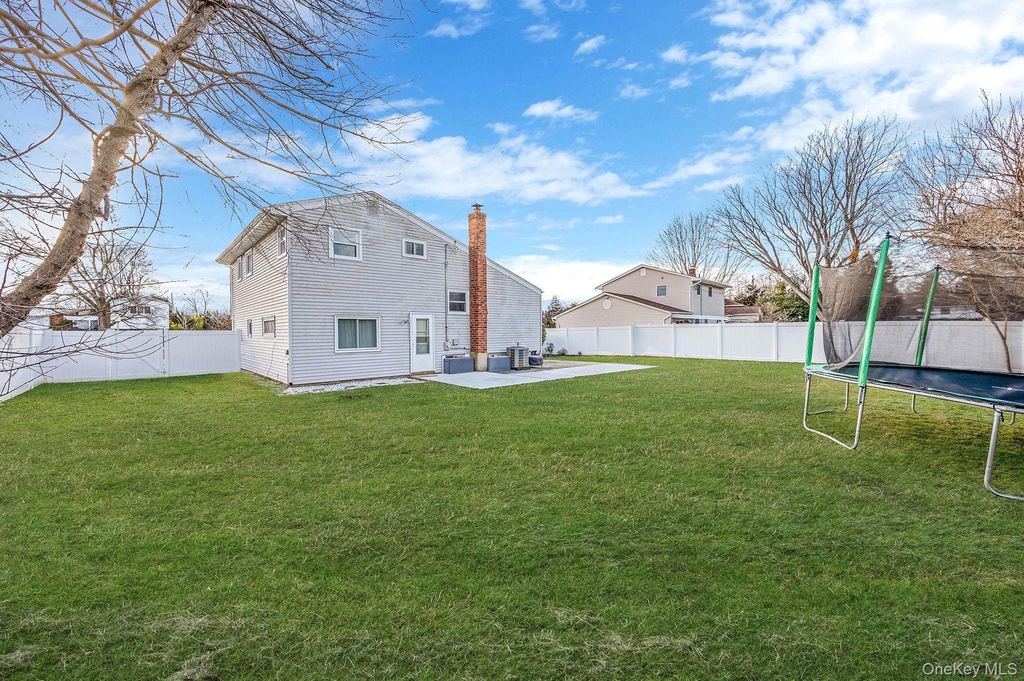 7 Seneca Drive Commack, NY 11725 - Photo 32 of 40 Back of property featuring a patio, a fenced backyard, and a chimney