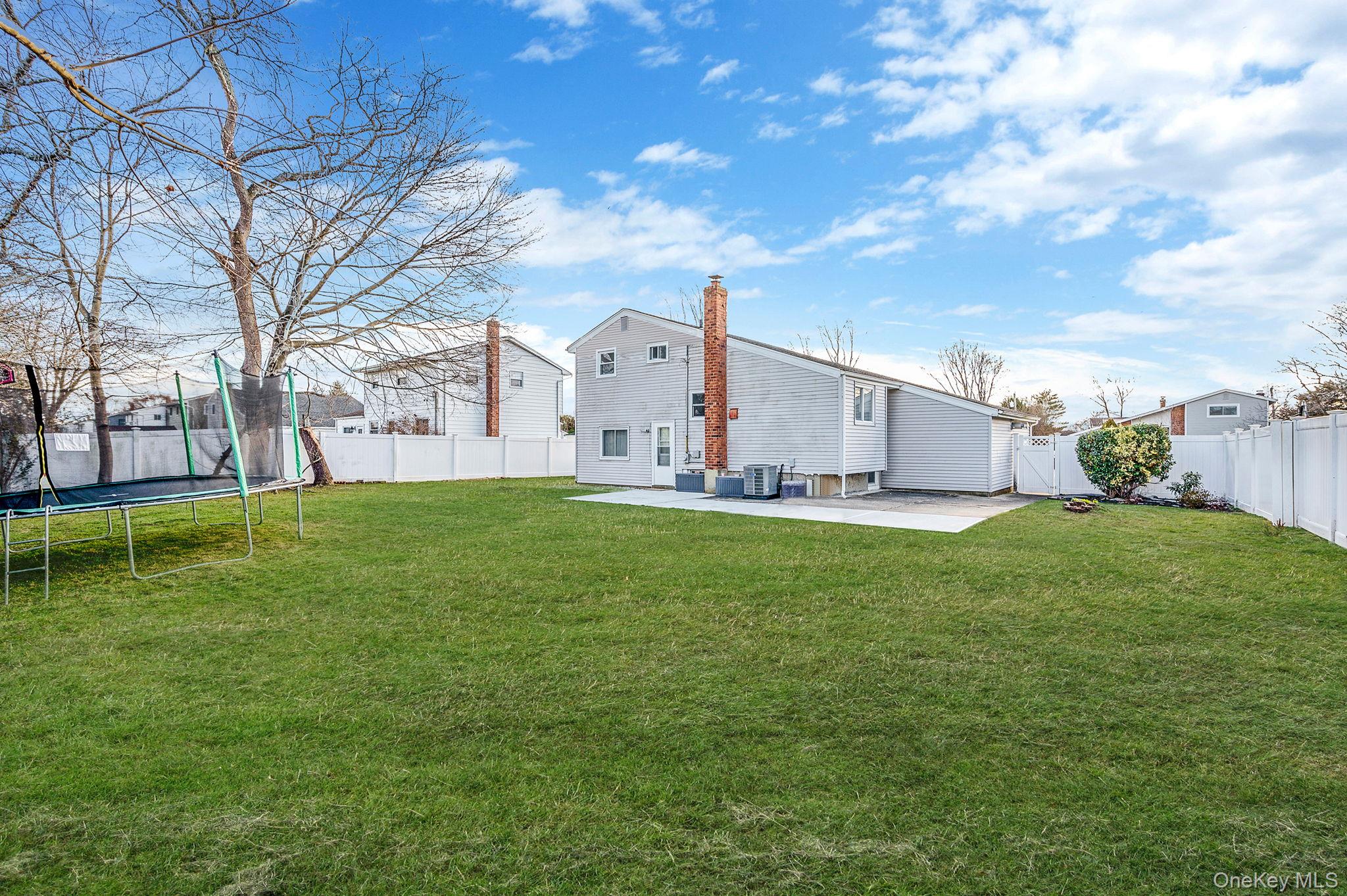 7 Seneca Drive Commack, NY 11725 - Photo 34 of 40 Rear view of property featuring a patio, a fenced backyard, a chimney, and a gate