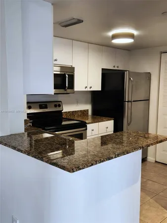a kitchen with granite countertop white cabinets and stainless steel appliances