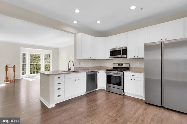 a large kitchen with stainless steel appliances granite countertop a stove a sink dishwasher a refrigerator and a microwave oven with wooden floor