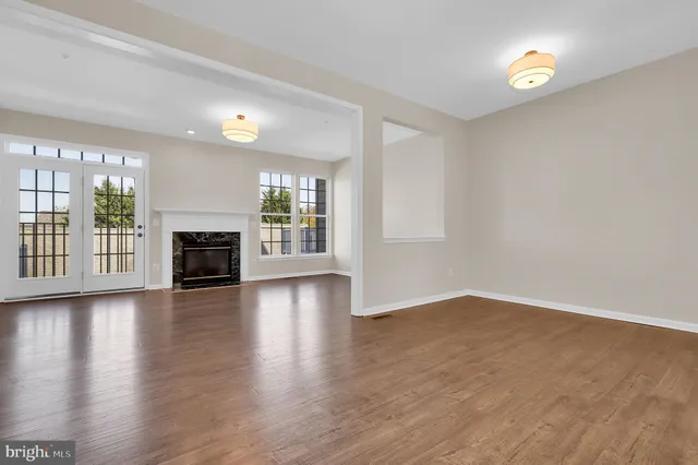an empty room with wooden floor fireplace and windows