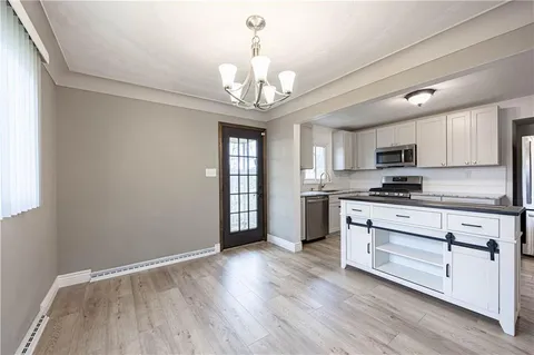 a kitchen with granite countertop wooden floors stainless steel appliances and a window